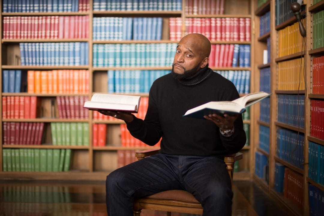 aaron davis holding books in both hands with bookshelves in the background