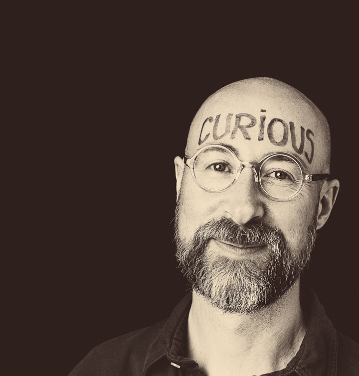 a headshot of stuart chittenden with the word "curios" written on his forehead